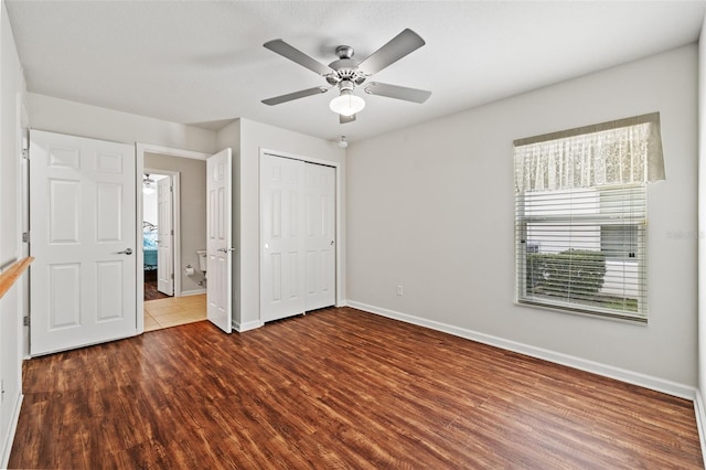 unfurnished bedroom featuring dark wood-style floors, a closet, ceiling fan, and baseboards