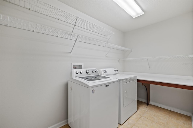 washroom with laundry area, washer and clothes dryer, light tile patterned flooring, and baseboards