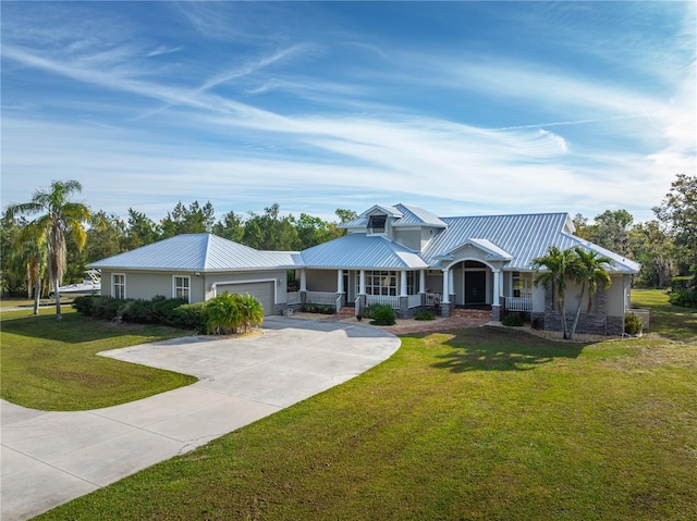 view of front of house with driveway, a garage, metal roof, covered porch, and a front lawn