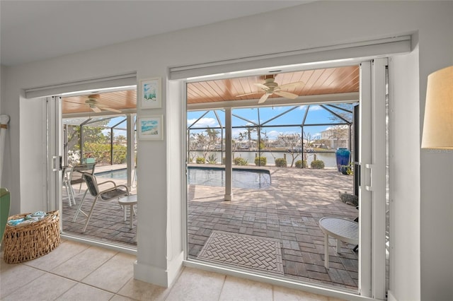 doorway to outside with a ceiling fan, a sunroom, and a water view