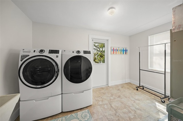 washroom featuring laundry area, baseboards, and washer and dryer