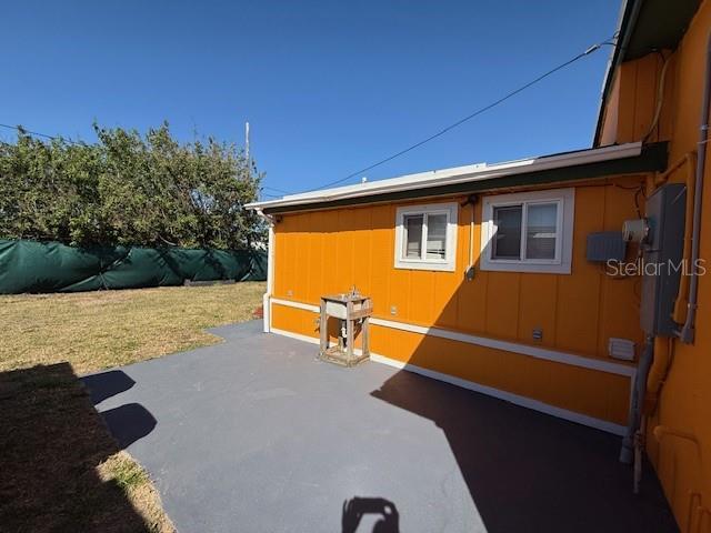 view of side of home with a yard, a patio, and fence