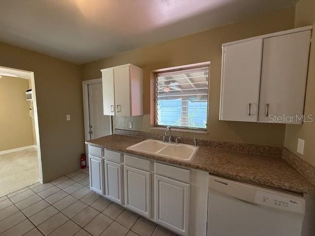 kitchen with light tile patterned floors, white dishwasher, white cabinetry, and a sink