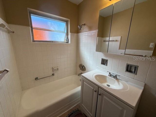 bathroom featuring tile walls, bathtub / shower combination, and vanity