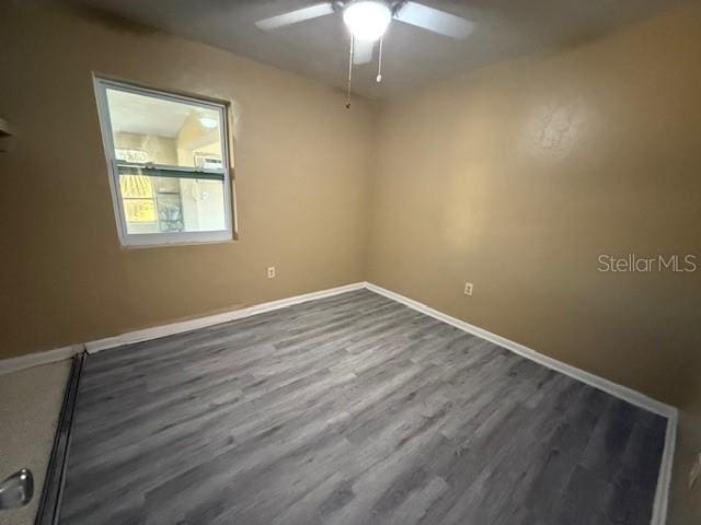 empty room featuring dark wood-type flooring, ceiling fan, and baseboards