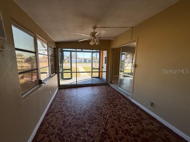 unfurnished sunroom with a ceiling fan