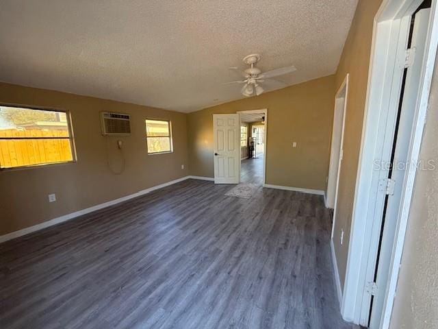 spare room featuring dark wood-type flooring, vaulted ceiling, a textured ceiling, ceiling fan, and baseboards