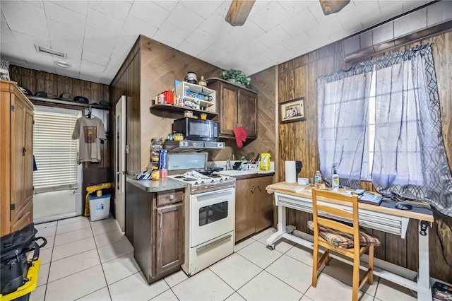 kitchen with black microwave, wood walls, visible vents, open shelves, and white gas range