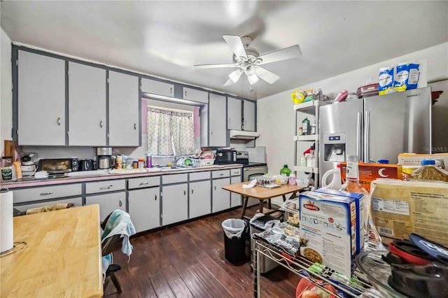 kitchen featuring stainless steel appliances, light countertops, dark wood-type flooring, a ceiling fan, and under cabinet range hood