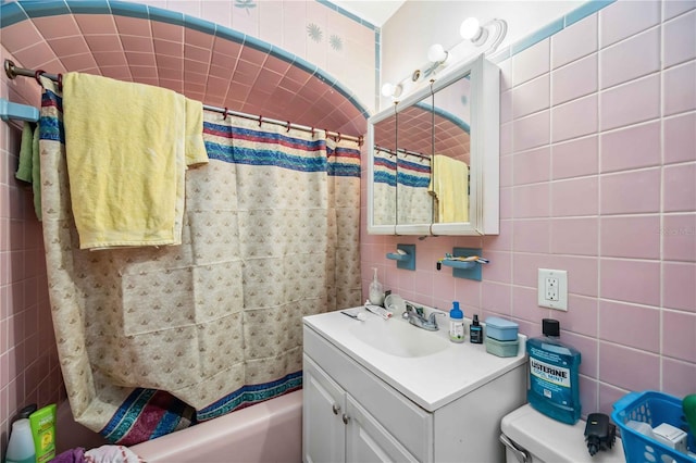 bathroom with toilet, vanity, and tile walls