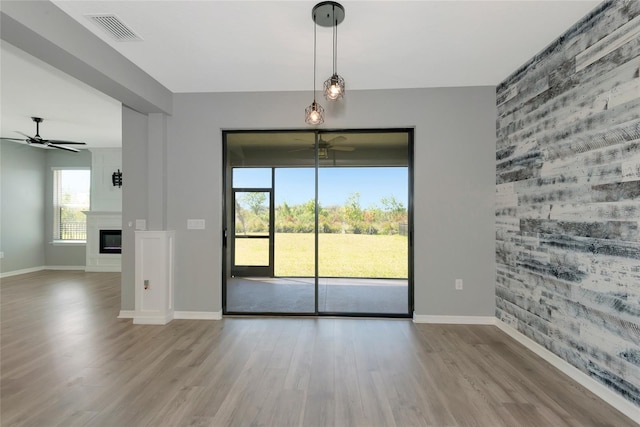 unfurnished room featuring a fireplace, wood finished floors, visible vents, and ceiling fan