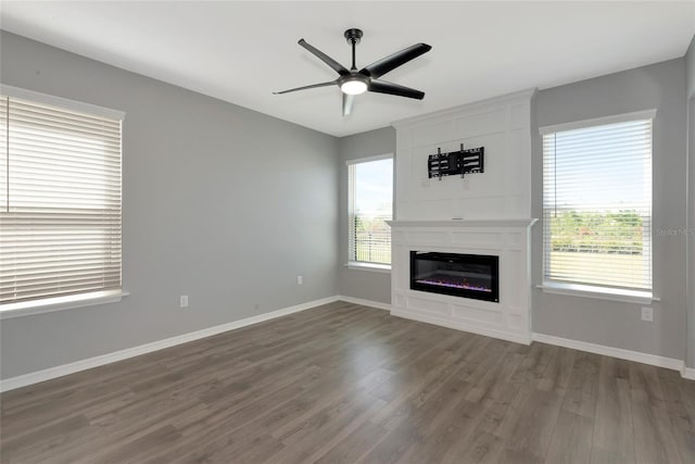 unfurnished living room with dark wood-type flooring, baseboards, and a wealth of natural light