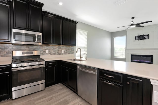 kitchen featuring appliances with stainless steel finishes, light countertops, dark cabinetry, and a sink