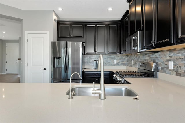 kitchen featuring stainless steel appliances, dark cabinetry, decorative backsplash, and light countertops