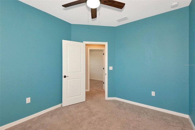 carpeted empty room with visible vents, a ceiling fan, and baseboards