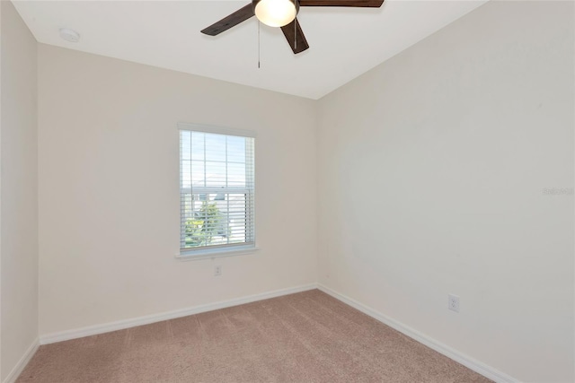 spare room featuring a ceiling fan, baseboards, and light carpet