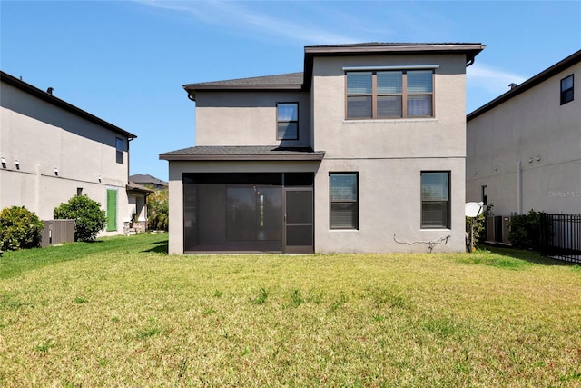 back of property with fence, a sunroom, stucco siding, central air condition unit, and a lawn