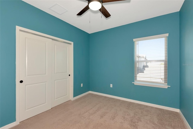 unfurnished bedroom featuring a ceiling fan, carpet, visible vents, baseboards, and a closet