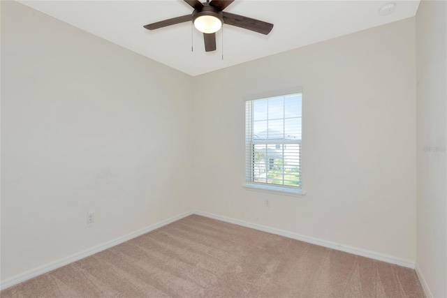 spare room featuring baseboards, light colored carpet, and ceiling fan