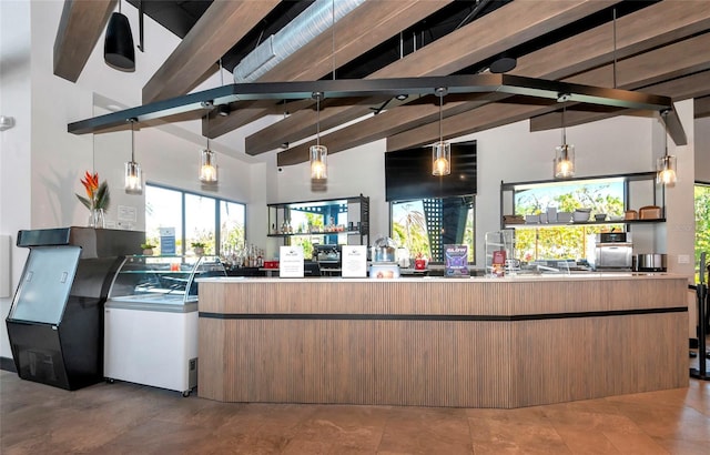 kitchen with beam ceiling, hanging light fixtures, and high vaulted ceiling