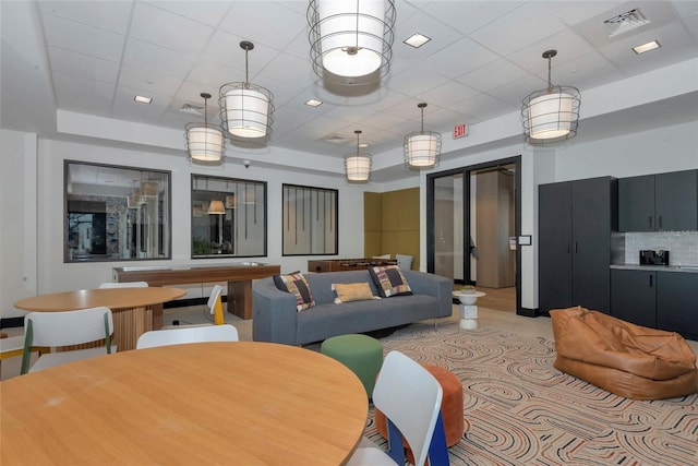 living room featuring visible vents, a raised ceiling, and a paneled ceiling