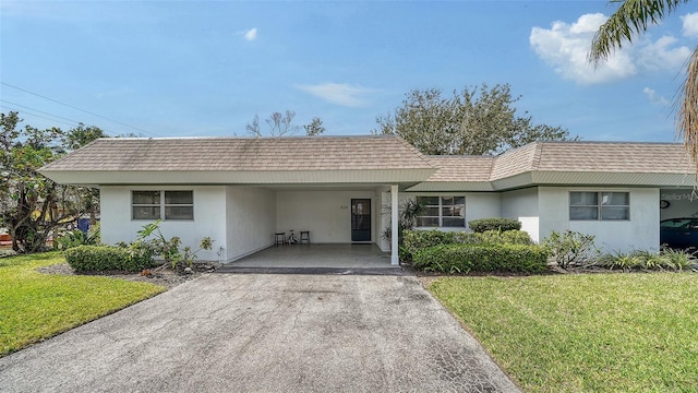 ranch-style house featuring mansard roof, roof with shingles, concrete driveway, and a front lawn