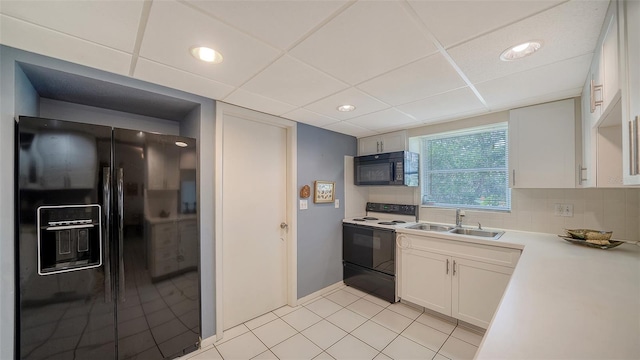 kitchen featuring backsplash, light countertops, white cabinets, black appliances, and a sink