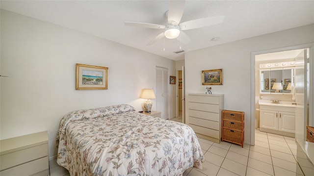 bedroom with light tile patterned floors, visible vents, a closet, a textured ceiling, and connected bathroom