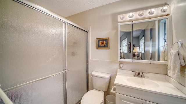 full bathroom featuring vanity, a shower stall, a textured ceiling, tile walls, and toilet