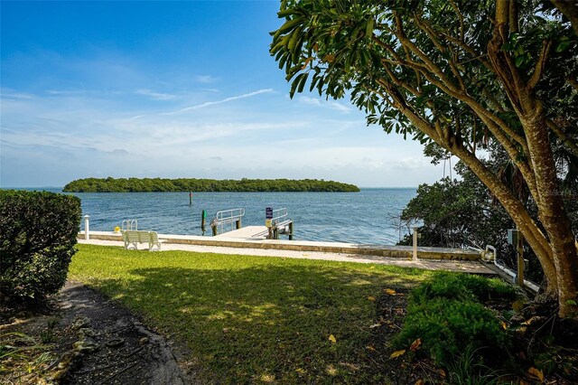 view of dock with a lawn and a water view