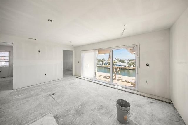 unfurnished room with visible vents, a water view, and a wealth of natural light