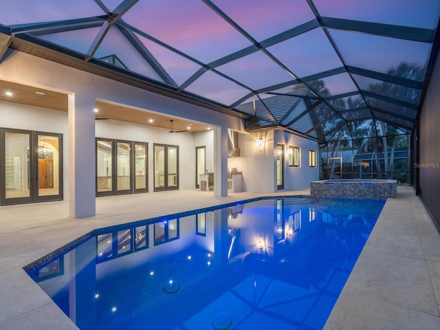 view of swimming pool featuring glass enclosure, a pool with connected hot tub, ceiling fan, french doors, and a patio area