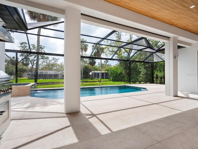 outdoor pool with a patio area, glass enclosure, and a yard