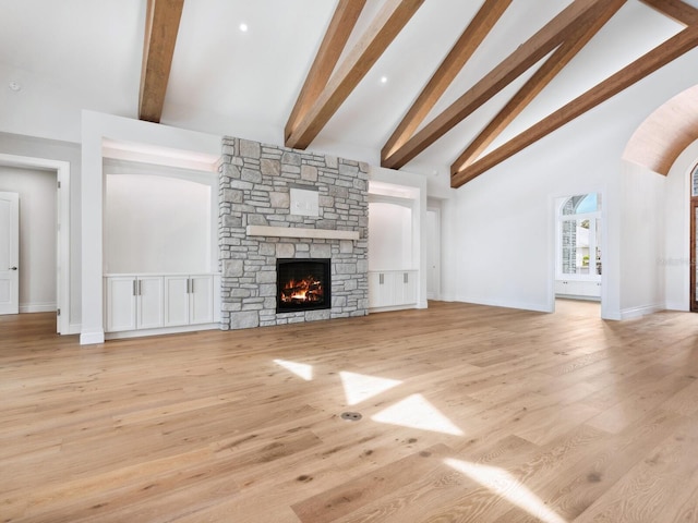 unfurnished living room featuring baseboards, high vaulted ceiling, a stone fireplace, beamed ceiling, and light wood-type flooring