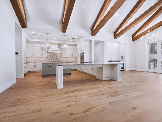 kitchen featuring a kitchen island, vaulted ceiling with beams, light wood-style floors, a kitchen breakfast bar, and tasteful backsplash