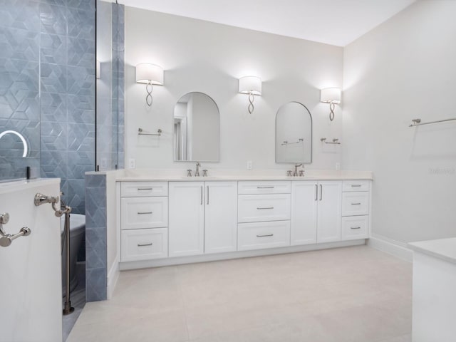 bathroom with baseboards, double vanity, a sink, tile patterned flooring, and walk in shower