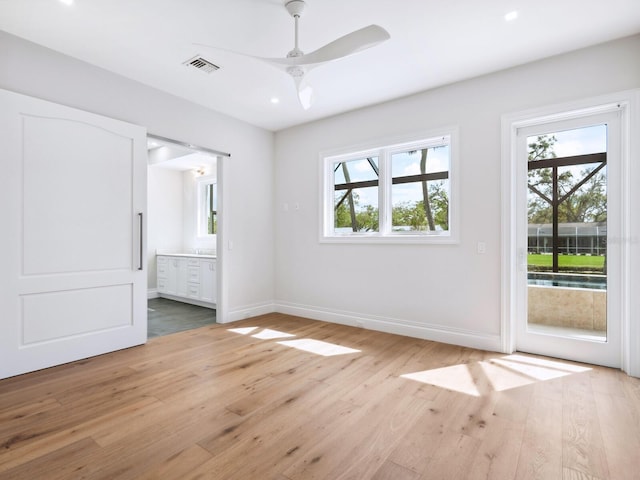 unfurnished bedroom featuring access to exterior, multiple windows, light wood finished floors, and baseboards