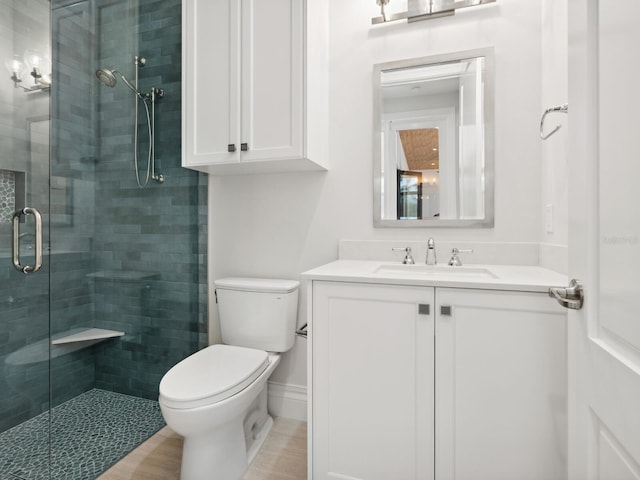 bathroom featuring baseboards, toilet, a stall shower, and vanity