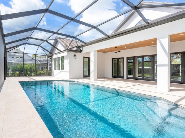 pool with glass enclosure, a patio, and a ceiling fan