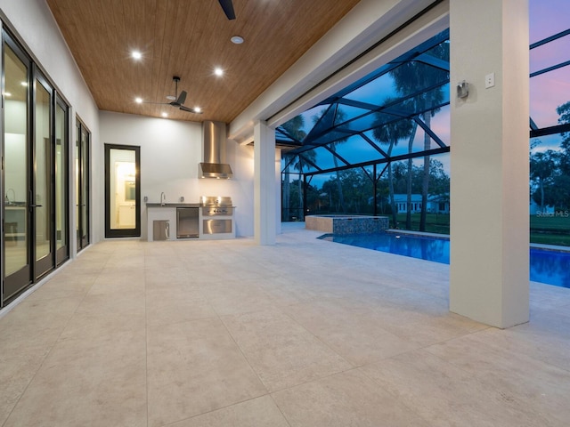 interior space featuring a ceiling fan, an outdoor kitchen, a pool with connected hot tub, a sink, and a lanai