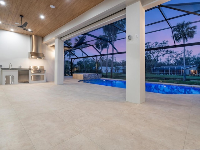 pool at dusk with a pool with connected hot tub, glass enclosure, a patio area, area for grilling, and a grill