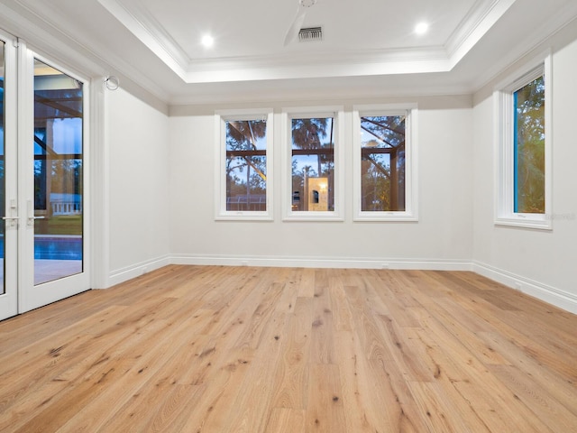 spare room featuring baseboards, a raised ceiling, light wood-style floors, and crown molding