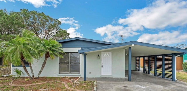 view of front facade featuring a carport, concrete driveway, and stucco siding