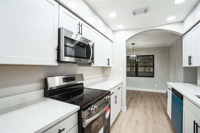 kitchen with visible vents, arched walkways, appliances with stainless steel finishes, light wood-style floors, and white cabinetry