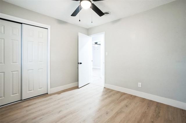 unfurnished bedroom featuring a closet, wood finished floors, a ceiling fan, and baseboards