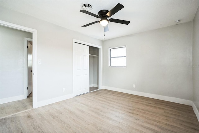 unfurnished bedroom featuring a closet, visible vents, baseboards, and wood finished floors