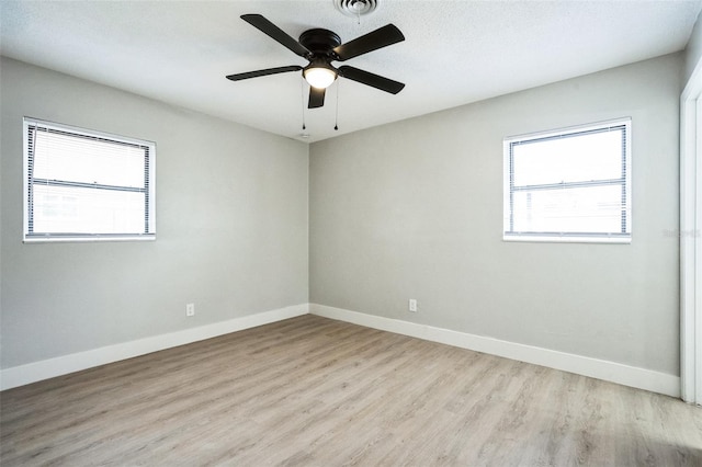 empty room featuring baseboards, a ceiling fan, visible vents, and light wood-style floors