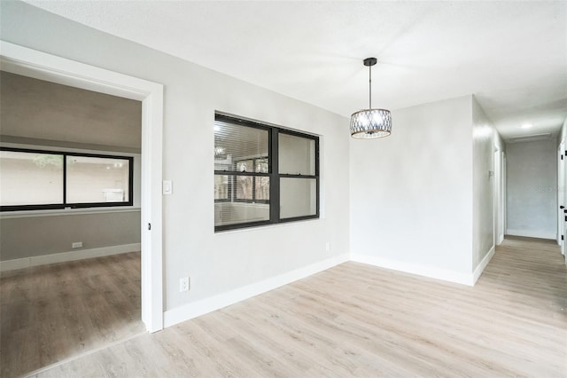 unfurnished room with a chandelier, baseboards, and wood finished floors