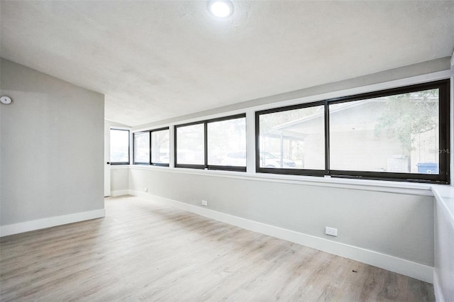 unfurnished room with lofted ceiling, baseboards, and wood finished floors