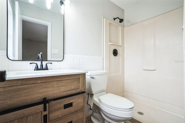 full bath featuring toilet, a shower, vanity, and tile walls